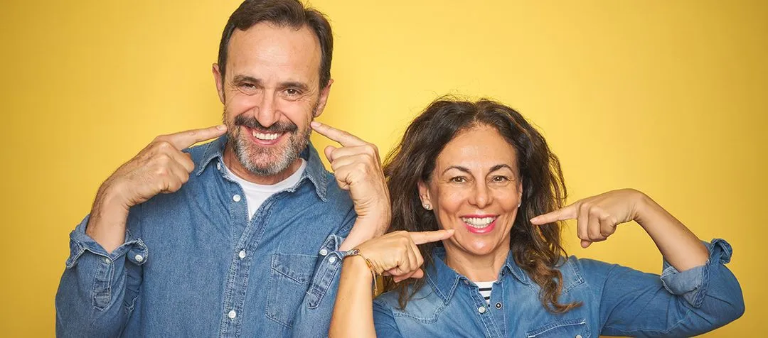 Man and Woman smiling pointing to their mouths